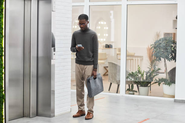 istock Black Young Man Waiting for Elevator in Office 1393425791