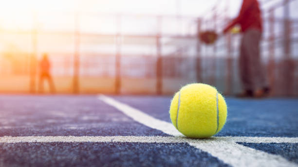 pelota amarilla en el suelo detrás de la red de pádel en cancha azul al aire libre. pádel - tennis court tennis ball racket fotografías e imágenes de stock