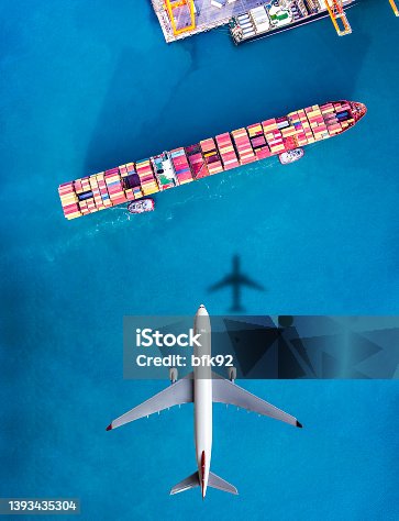 istock Airplane flying above cargo ship. 1393435304