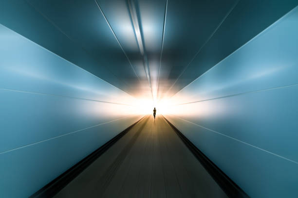 silhouette of running man toward ending with sunshine ahead in motion blurred tunnel, business success concept. stock photo