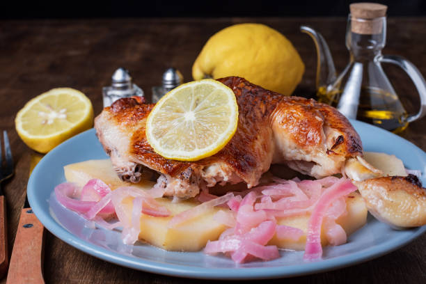 prato com coxa de frango limão, batatas e cebola roxa, azeite, limões, sal e pimenta ao fundo. close-up. - animal skin prepared potato chicken leg chicken - fotografias e filmes do acervo