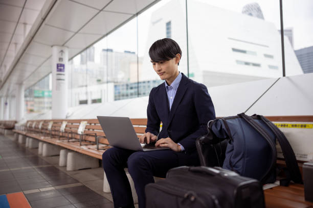 出張中にバス停で働く日本人ビジネスマン - outdoors business computer laptop ストックフォトと画像