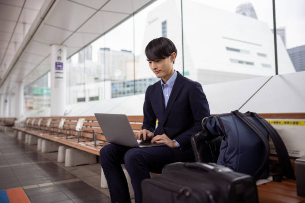 Japanese businessman working at bus station during business trip stock photo