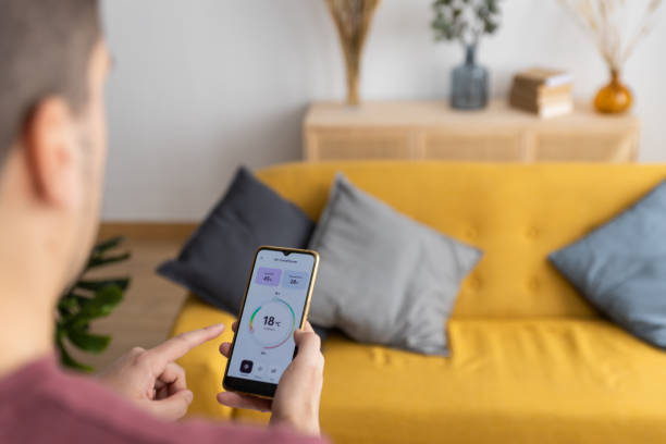 istock Over-the-shoulder view of a man using a smart home temperature control app 1393448295