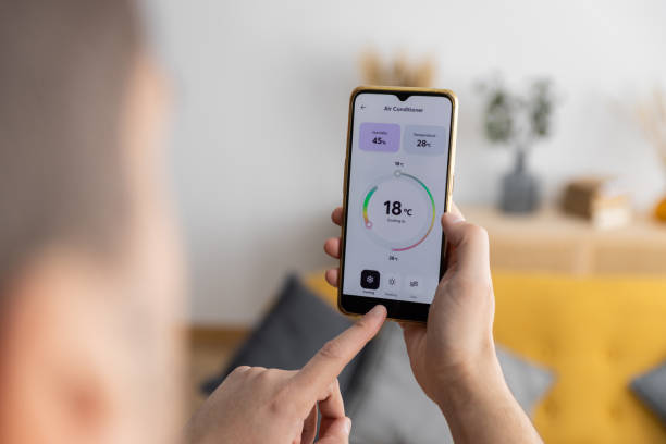 vue rapprochée d’un homme ajustant son climatiseur domestique avec une application pour téléphone intelligent. - room temperature photos et images de collection