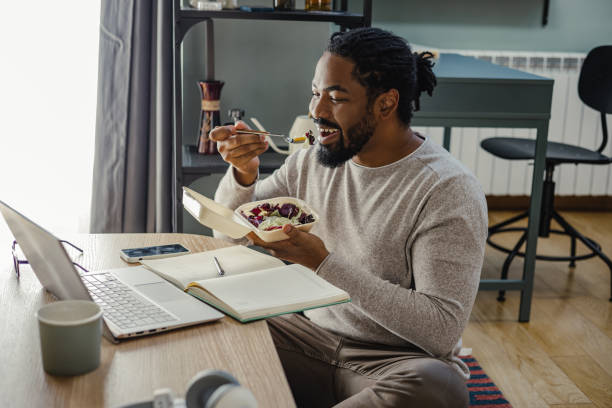 istock Man eating takeaway food while working on his laptop 1393453695