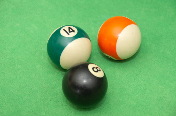 Action of a human is aiming to hitting the white snooker ball. Playing snooker activity photo, selective focus at the ball.