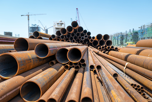 A pile of large steel pipes is piled on the construction site