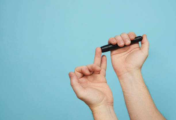 istock Man with lancet pen doing diabetes test, close-up 1393472857