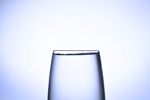 poured water into wine glass over white background, wide photo