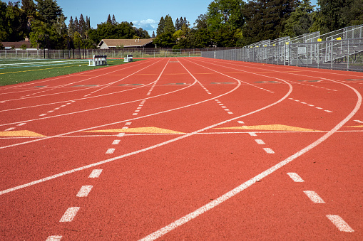 Low angle shot of high school running track.  New track, red synthetic rubber track with white lines.