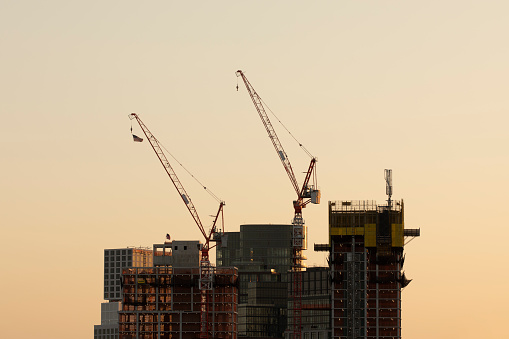 Construction cranes atop residential building developments in New York City.