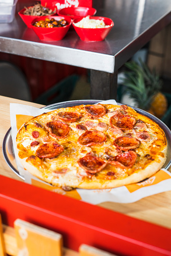 Pepperoni and cheese pizza is served ready to eat at the table of some customers of a food truck