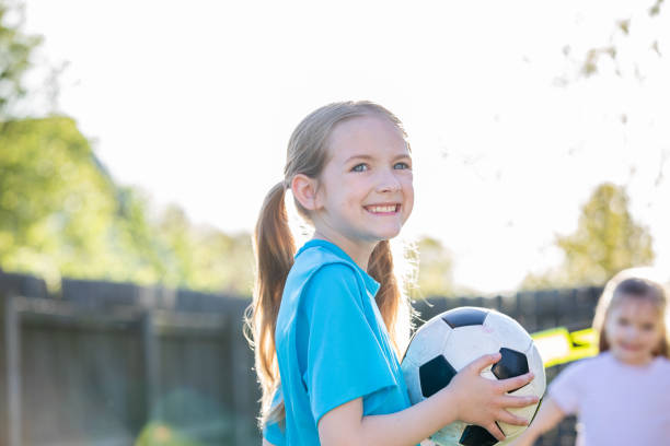 istock Adorable elementary age sisters playing soccer together in backyard at home 1393487953