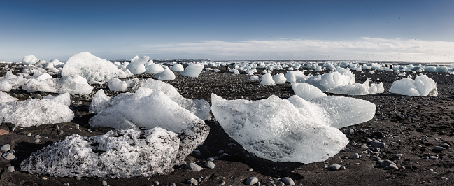 Iceland Jökulsarlon Lagoon Diamond Beach Stiched Panorama. View over the Black Beach - Diamond Beach with stranded Icebergs from the glacier lake lagoon of Jökulsarlon under sunny blue winter sky. Stiched Canon R5 XXL Panorama. Diamond Beach, Jokulsarlon, Vatnajökull National Park, Route 1, Southeast Iceland, Iceland, Nordic Countries, Northern Europe