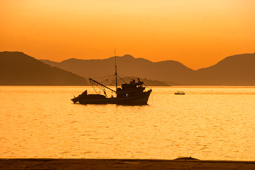 silhouette of a fishing boat on the red beach of Urca in Rio de Janeiro.