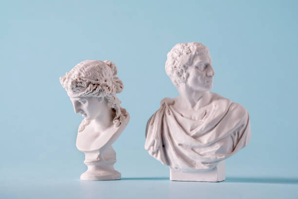 Two white Roman or antique style Grecian busts Two white Roman or Grecian antique style busts of young men over a blue background bust sculpture photos stock pictures, royalty-free photos & images