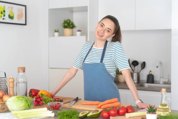 istock Young vegetarian woman cooking at kitchen, smiling at camera 1393501487