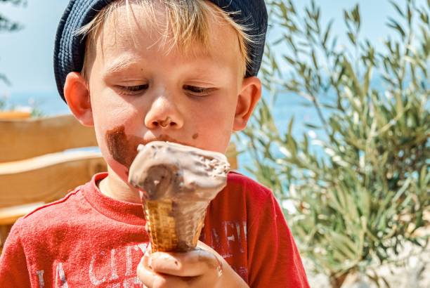 istock Blond boy enjoys eating chocolate ice cream getting dirty 1393503492
