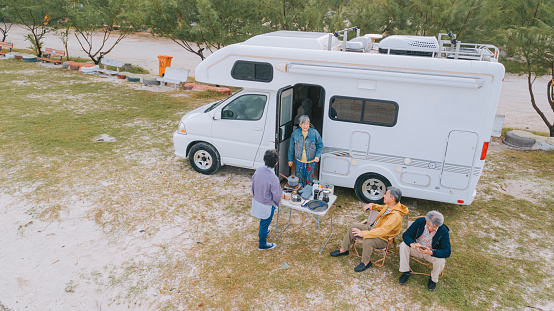 asian chinese senior friends enjoying outdoor moment at beach with motor home during weekend