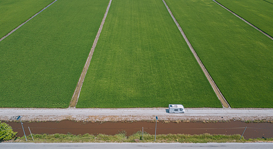 drone point of view campervan on country road cruise beside paddy field