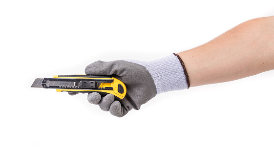 A gloved hand holds a cutter. Isolated on a white background. Close-up.