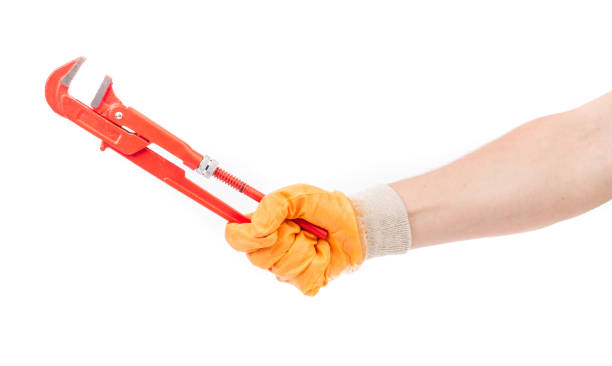 une main gantée tient une clé à pipe. - adjustable wrench wrench orange hand tool photos et images de collection