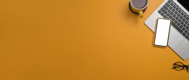 istock Top view laptop computer, smart phone, coffee cup and glasses on yellow background with copy space for your information content. 1393513109