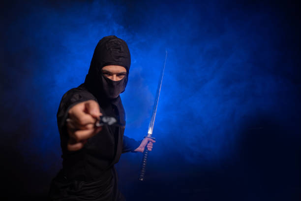 Medieval warrior ninja assassin throws shuriken in smoke.