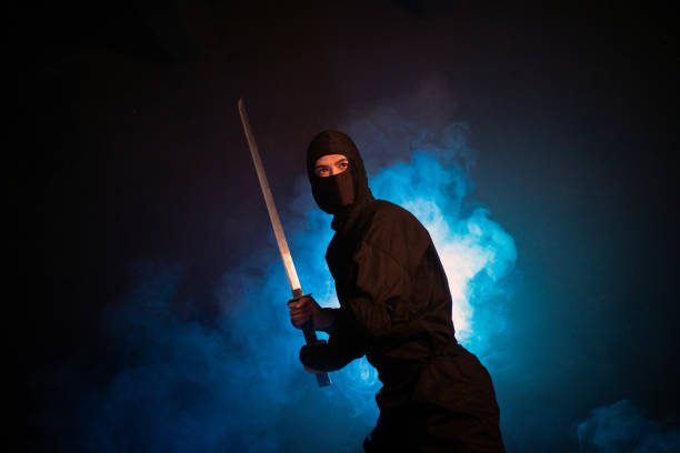 istock Medieval warrior assassin ninja with sword in aggressive pose in smoke 1393516409