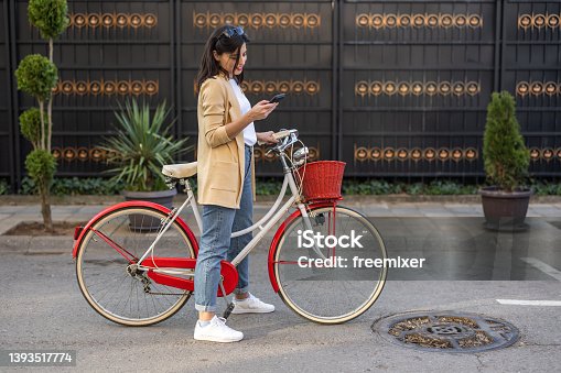 istock Young female tourist using phone while exploring city on vintage bicycle 1393517774