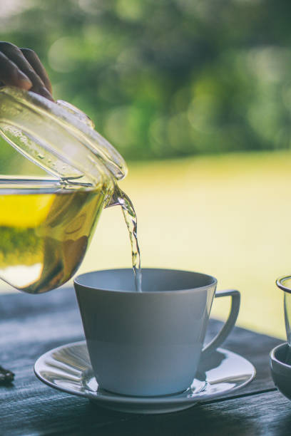 istock A clear glass teapot is poured into the glass in which it rests. 1393519414