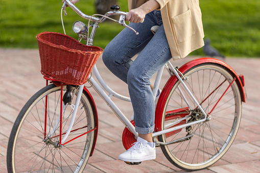 Close-up shot of unrecognizable young woman riding vintage bicycle in city park