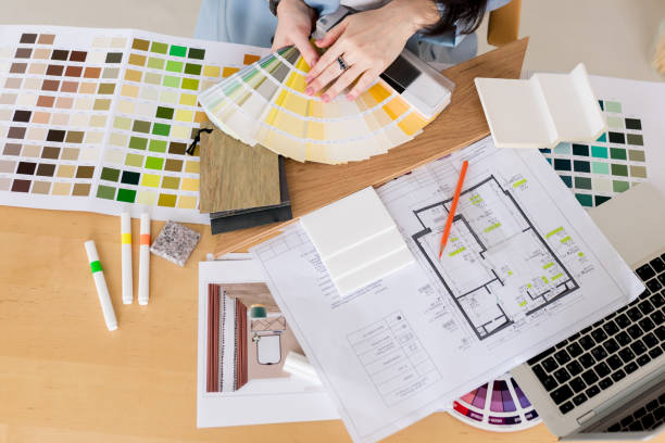 istock Woman architect working on interior renovation in workplace. Designer choosing color samples according to the visualization and blueprints of the project. Architecture and interior design concept. 1393519663