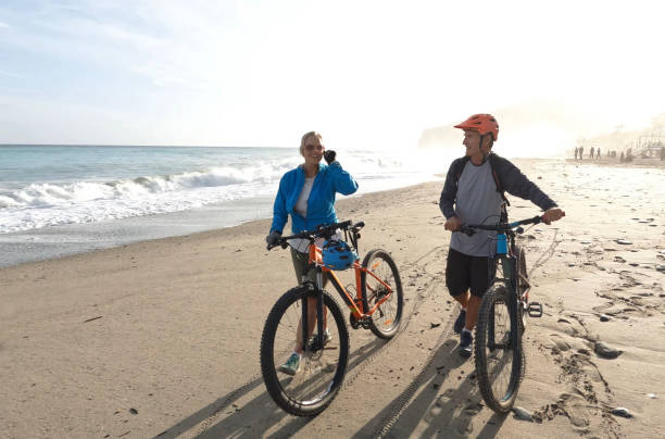 istock Mature couple push mountain bikes down beach 1393521933