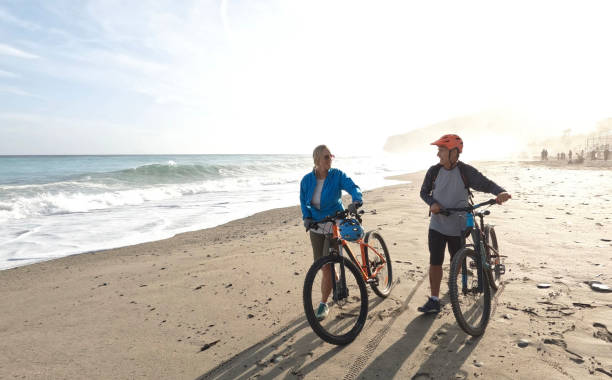 istock Mature couple push mountain bikes down beach 1393521942