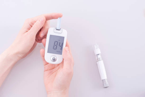 human using a glucometer to measure and test blood glucose levels from a finger. - diabetes blood sugar test insulin glucose imagens e fotografias de stock