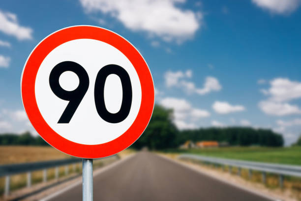 istock Speed limit sign with trees behind. Maximum ninety kilometers per hour. Safety on road background. White round sign red border line. 1393523458