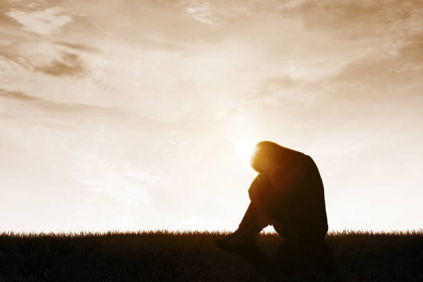 istock Depressed woman sitting on the meadow 1393526802
