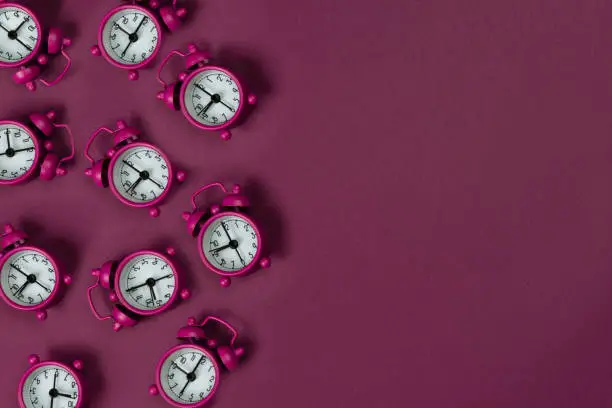 A lot of pink alarm clocks on pink background.