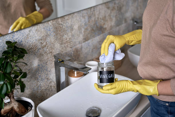mujer irreconocible limpiando grifo de baño con vinagre - vinagre fotografías e imágenes de stock