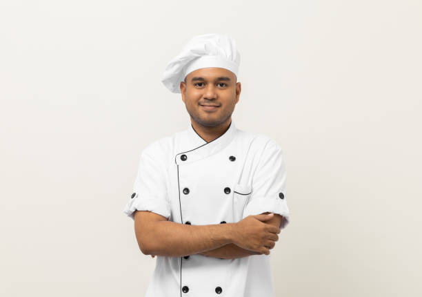istock Smiling Young handsome asian man chef in uniform with hat standing posting looking at camera on isolated white background. Cooking man Occupation chef or baker People in kitchen restaurant and hotel. 1393528654