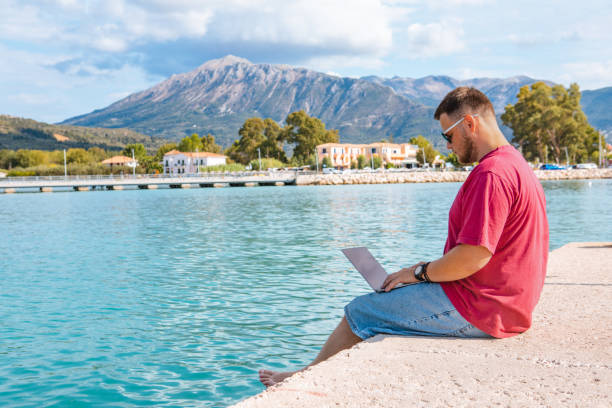 istock man freelancer working on laptop at city harbor bench 1393529914
