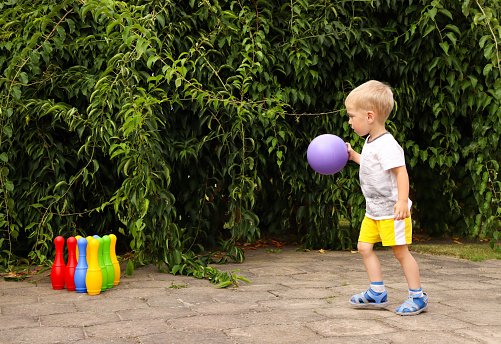 Toddler plays active outdoors games. bowling pins.