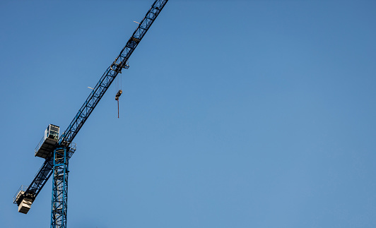 large industrial crane against blue sky. Constuction new building.