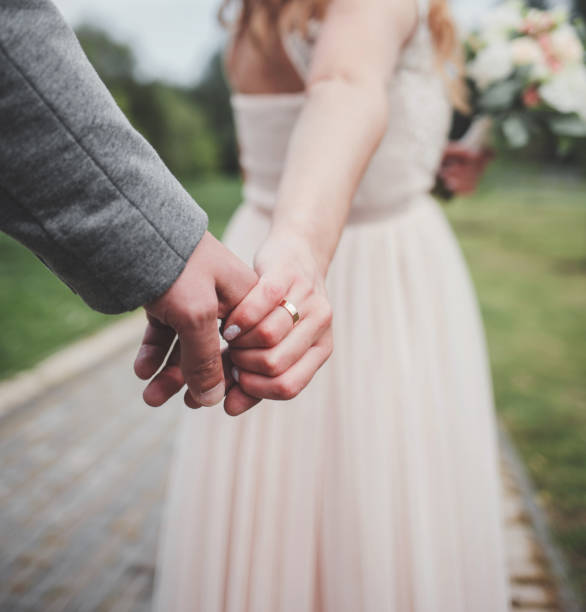 istock bride and groom holding each others hands 1393540596
