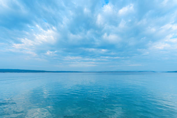 tranquila superficie de agua de mar con reflejo ondulado de las nubes y el cielo - morning croatia blue sea fotografías e imágenes de stock