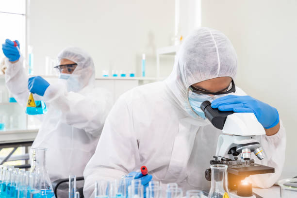 istock Researcher in laboratory personal protective equipment suit or PPE conduct experiment with biohazard virus using microscope to discover vaccine, science and medical concept. 1393546490