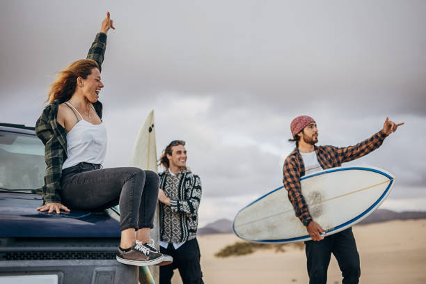 Three friends taking surfboards and going to beach to surf stock photo