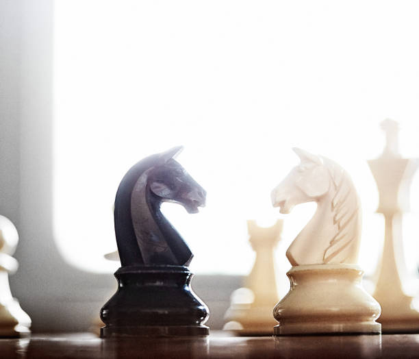 istock Atmospheric shot of rival knights confronting each other during a chess game, back lit by a window 1393549208
